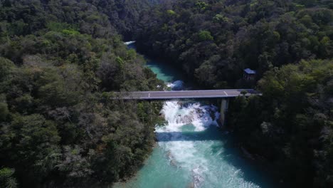 Retrocediendo-Desde-Arriba-De-Un-Mágico-Río-Turquesa-En-La-Selva-De-Chiapas,-México,-Un-Puente-Que-Cruza-El-Río