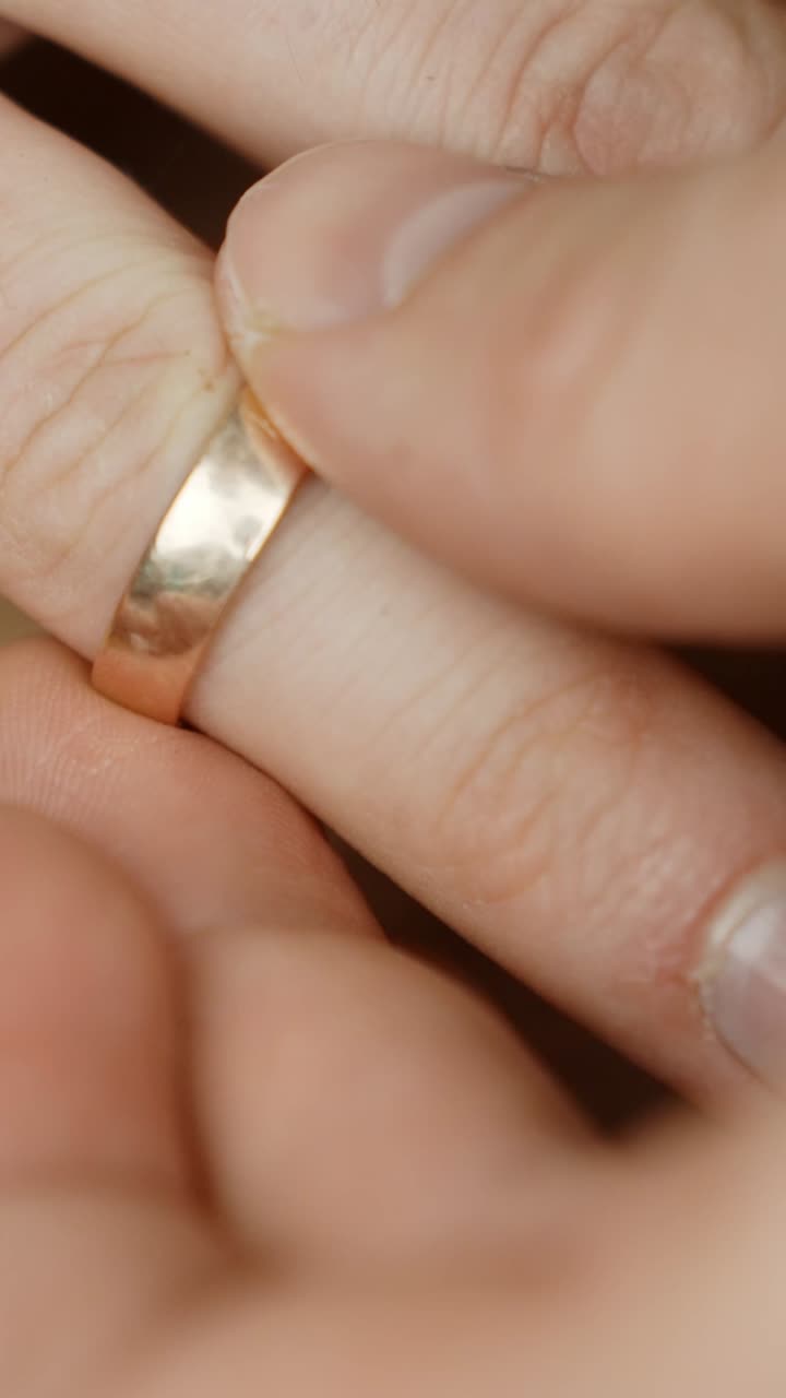 Person wears golden wedding ring, close up vertical view