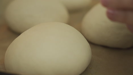 Brushing-egg-wash-over-some-burger-buns-dough,-ready-to-be-baked-in-the-oven