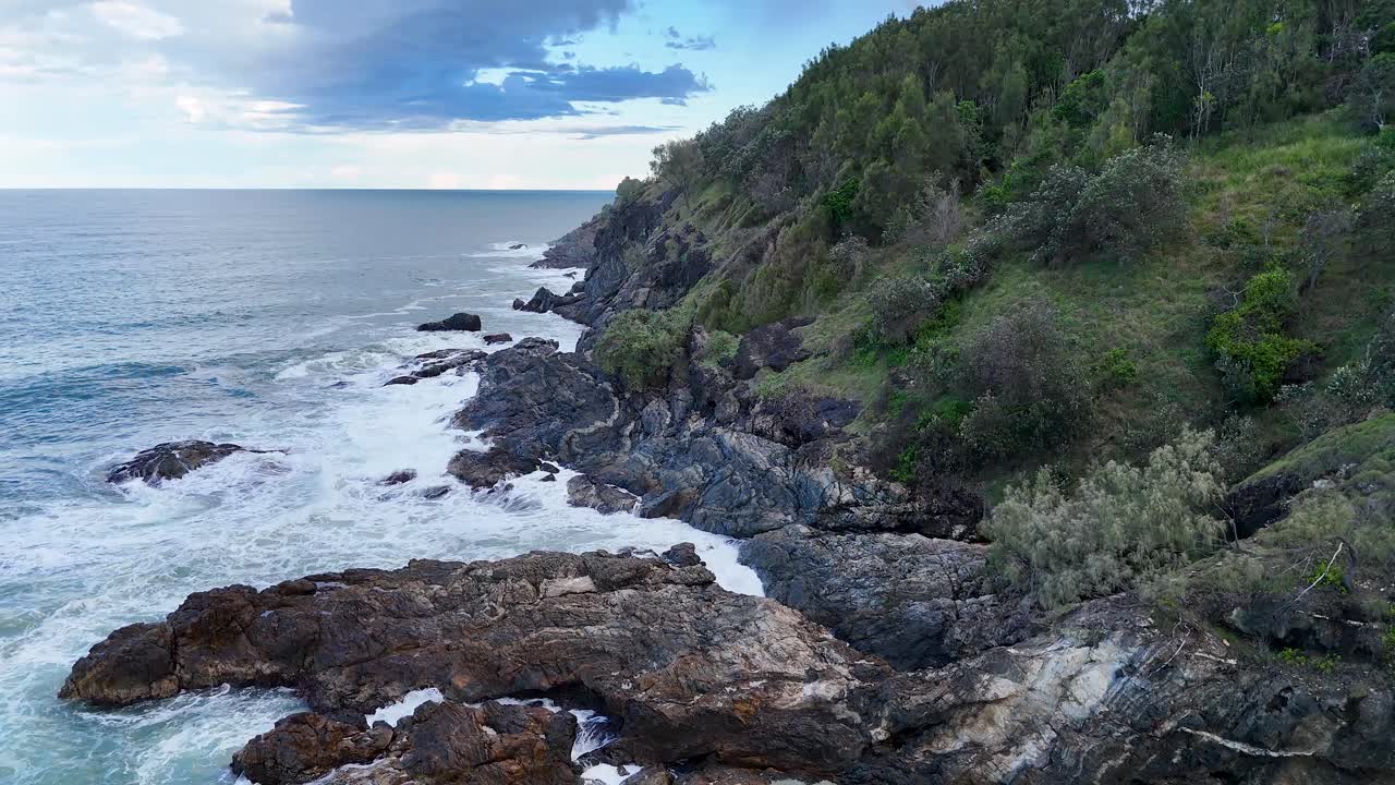 Aerial footage of rugged coastline and lush greenery at Charlesworth Bay Beach, Coffs Harbour, with dynamic waves and natural lighting