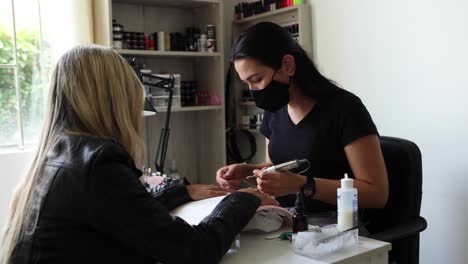 master polishing nails of female customer with electric file