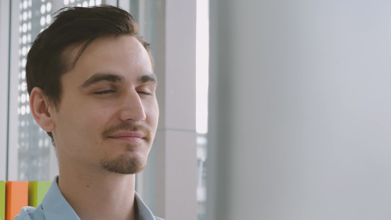 Young caucasian businessman looking at the monitor of a personal computer and smiles, working in a home office close-up