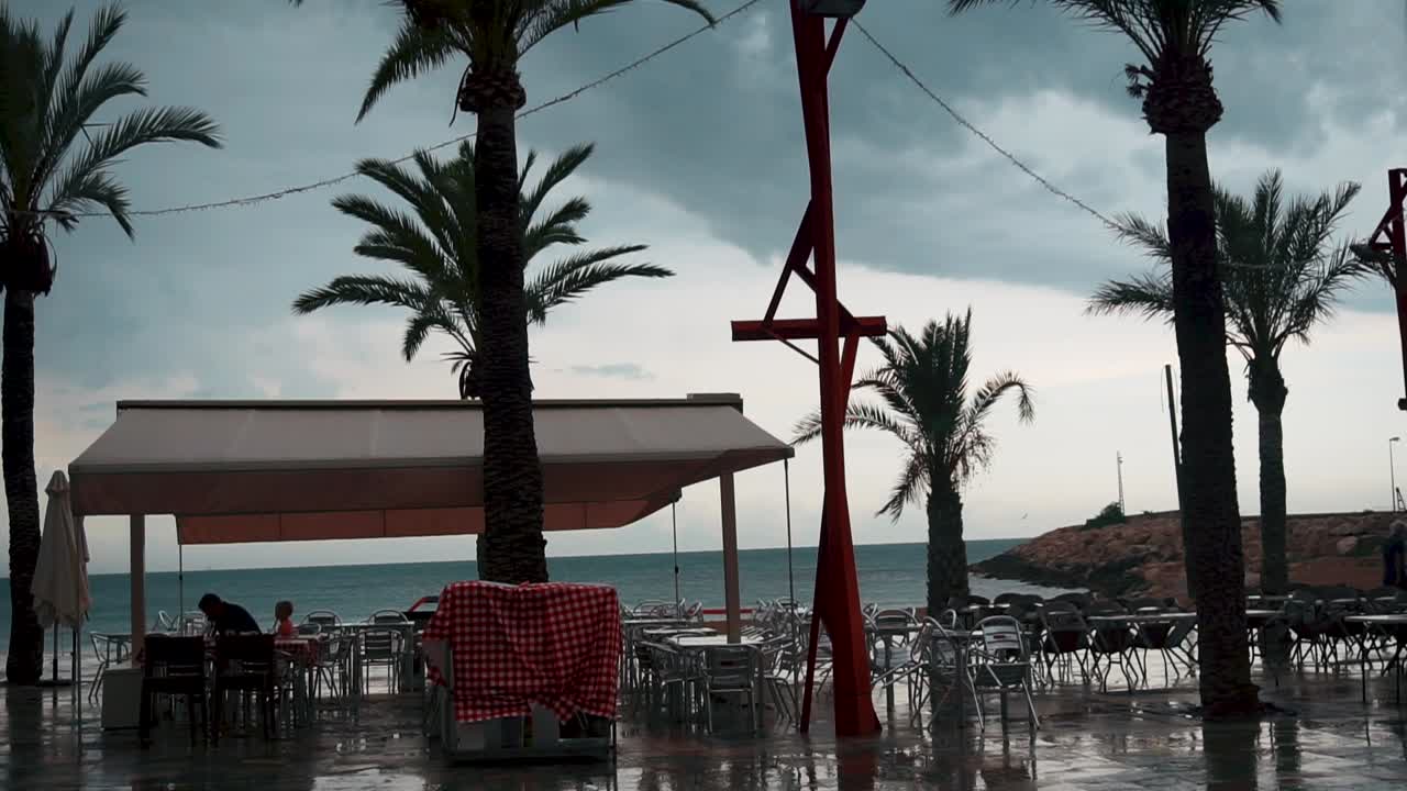 Few People In An Open Pavilion By The Sea In Vinaros, Spain On A Stormy Weather - wide shot