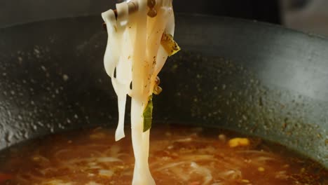 preparing delicious noodle soup in a wok