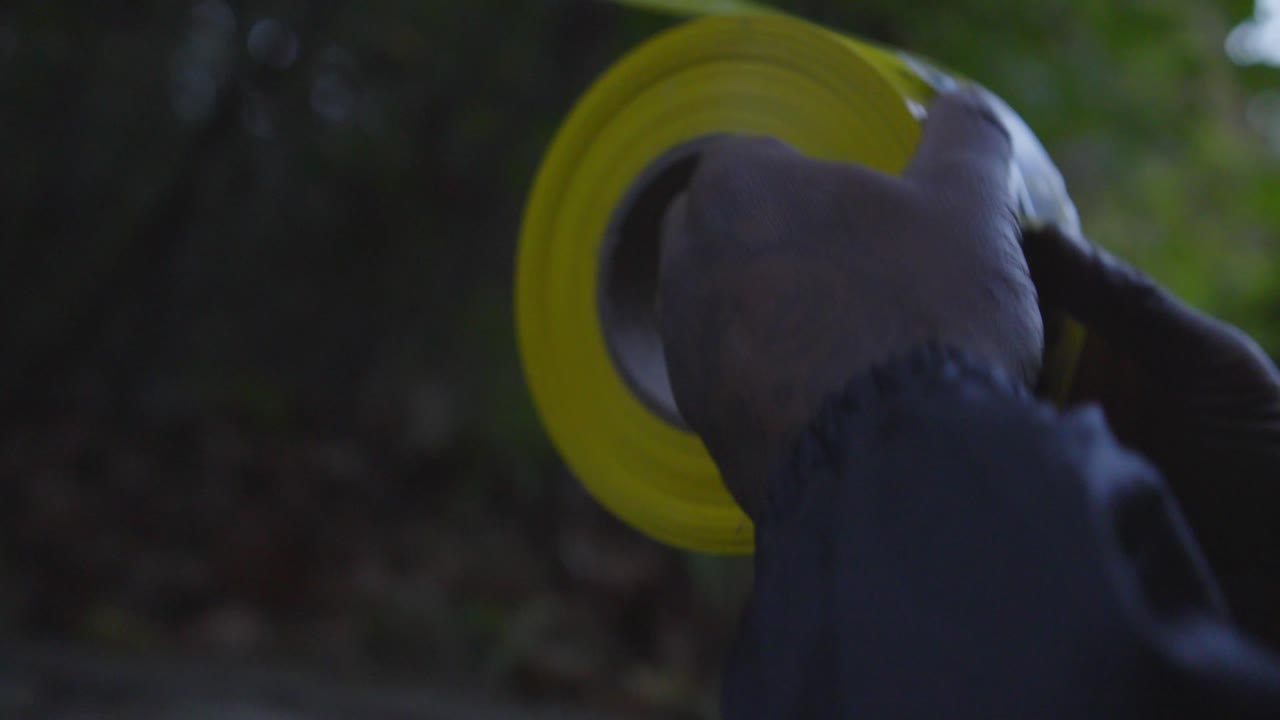 黒人男性が森林地帯で注意テープを巻き上げている