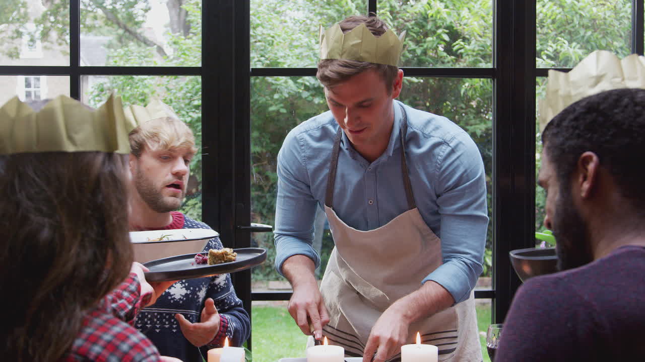 grupo de amigos sentados alrededor de la mesa de comedor en casa mientras se sirve la cena de navidad vegetariana