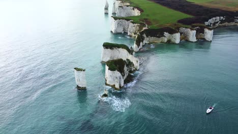 drone shot of old harry rocks with a boat in the isle of purbeck, england