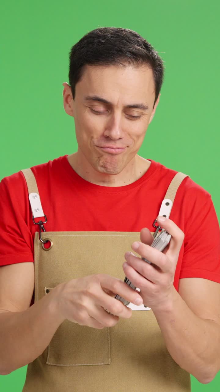 Happy entrepreneur counting and showing money on green screen