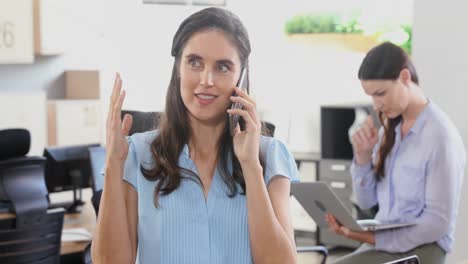 ejecutiva hablando por teléfono móvil mientras un colega trabaja en segundo plano 4k
