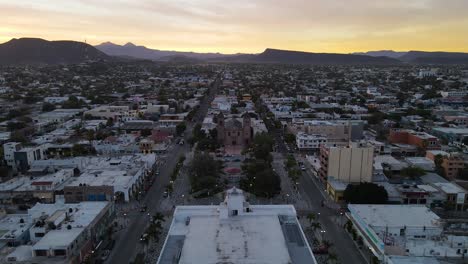 Aerial:-beautiful-sunset-over-La-Paz-city-buildings-in-Mexico,-Baja-California