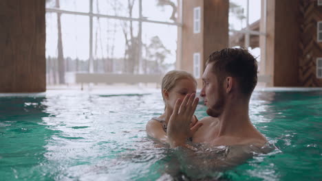happy-father-and-his-little-daughter-is-swimming-together-in-pool-of-modern-new-wellness-center