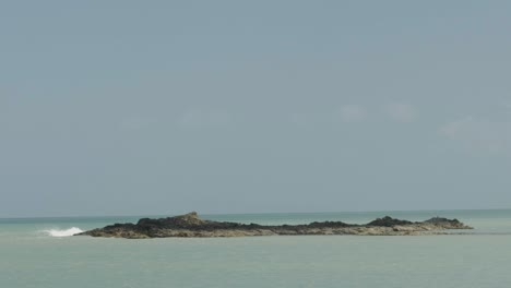 Cresta-De-La-Ola-Llevada-Por-La-Brisa-De-Verano-Y-Una-Pequeña-Isla-Rocosa-En-Un-Día-Soleado-Y-Claro