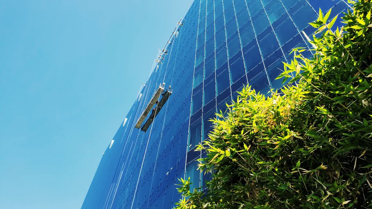 Window cleaning workers on a high swing stage suspended scaffold off an office corporate building