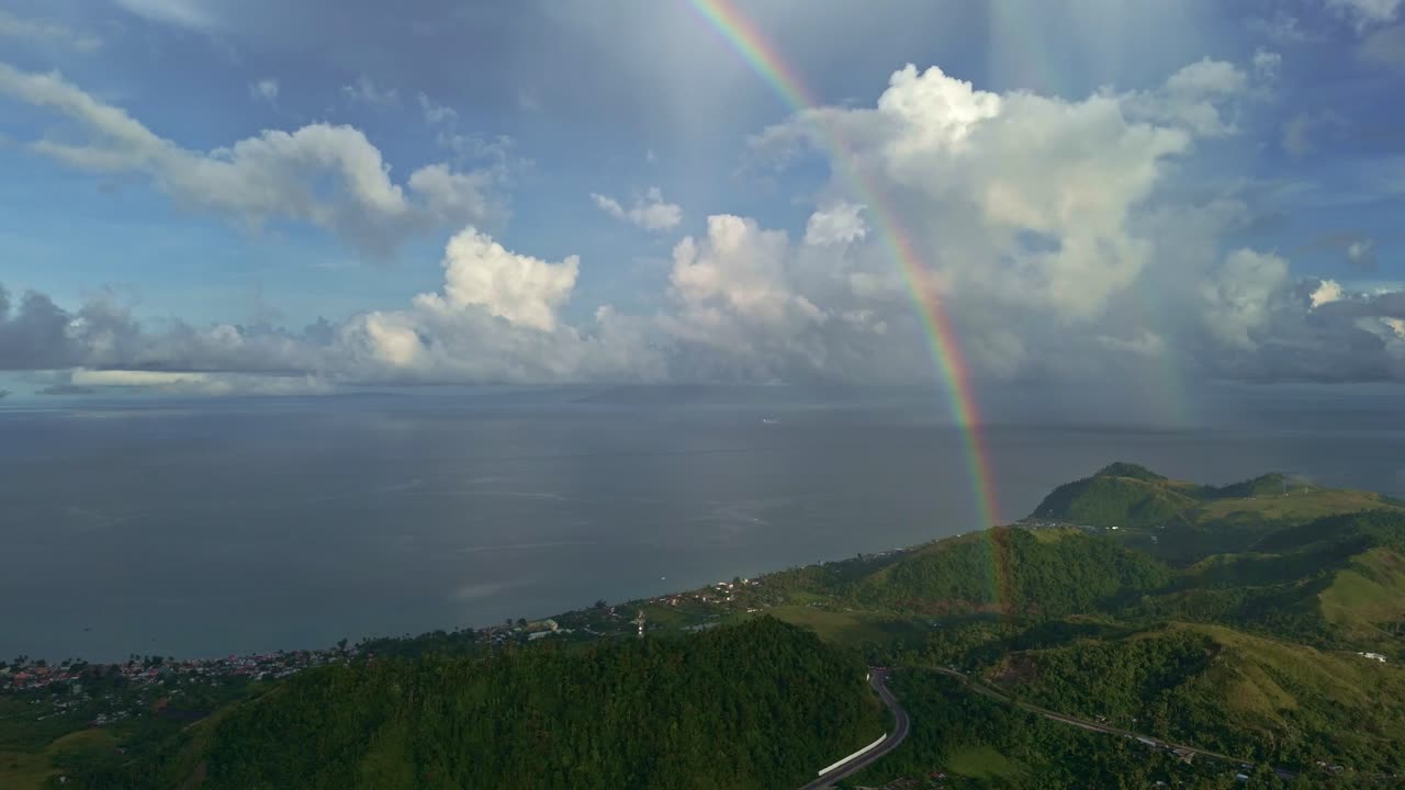 hermoso arco iris 4k de derecha a izquierda panorámica aérea del arco iris en la lluvia sobre el océano y las montañas
