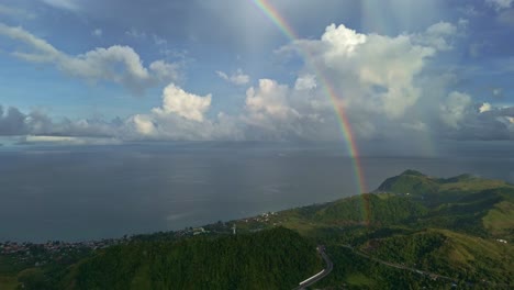 beautiful rainbow 4k right to left panning aerial of rainbow in the rain over ocean and mountains