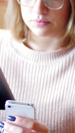 mujer usando tableta digital y teléfono móvil en la sala de estar