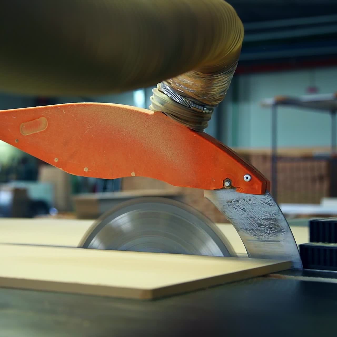 Machine-tool for cutting wood. Man pushing a wooden board to cut it with automatic saw equipment. Blurred backdrop