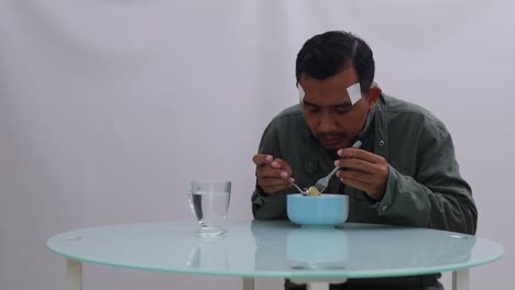 asian man in jacket shivering while eating boiled noodles on the table