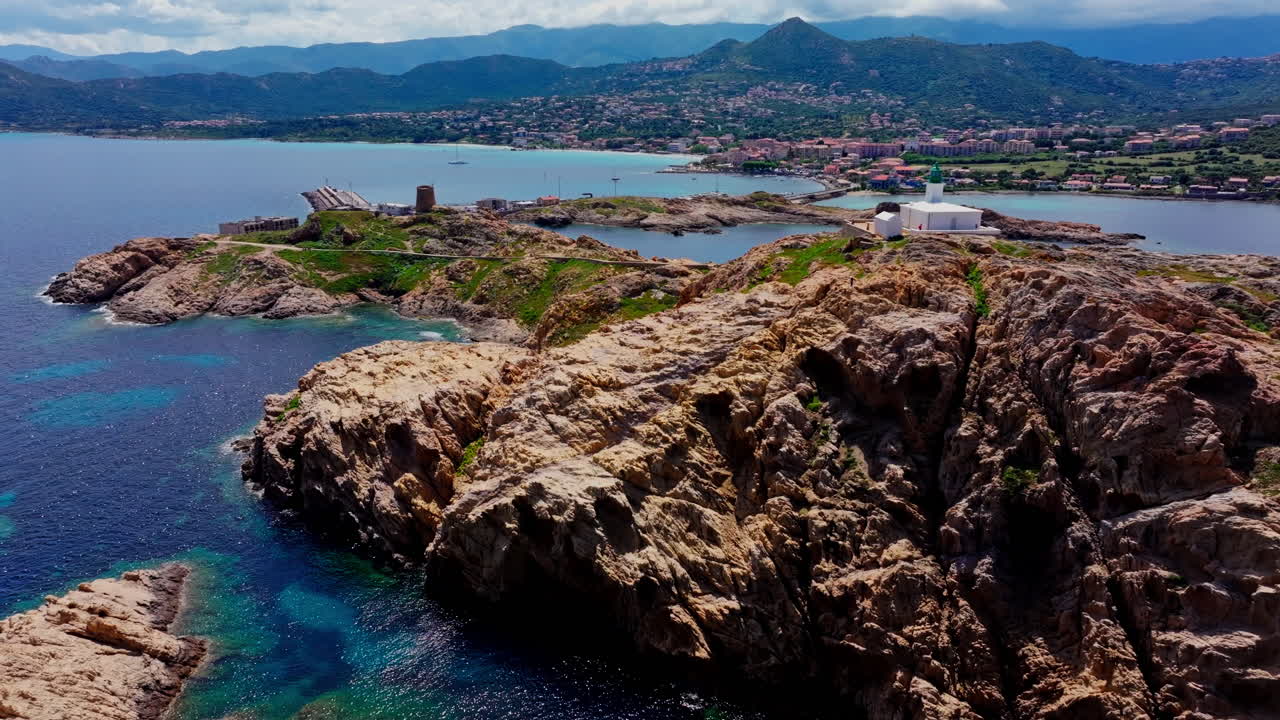 Aerial drone shot over Ile de la Pietra at the coastal town of Ile-Rousse in the Balagne region in Corsica, France. View of the White lighthouse on top of the cliff overlooking the landscape