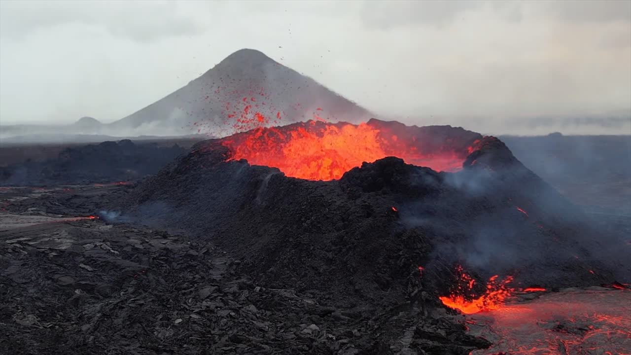 Filmato in super slow-motion di un vulcano in eruzione in Islanda, che cattura esplosioni di lava dal cratere e lava fusa che scorre sul terreno vulcanico scuro