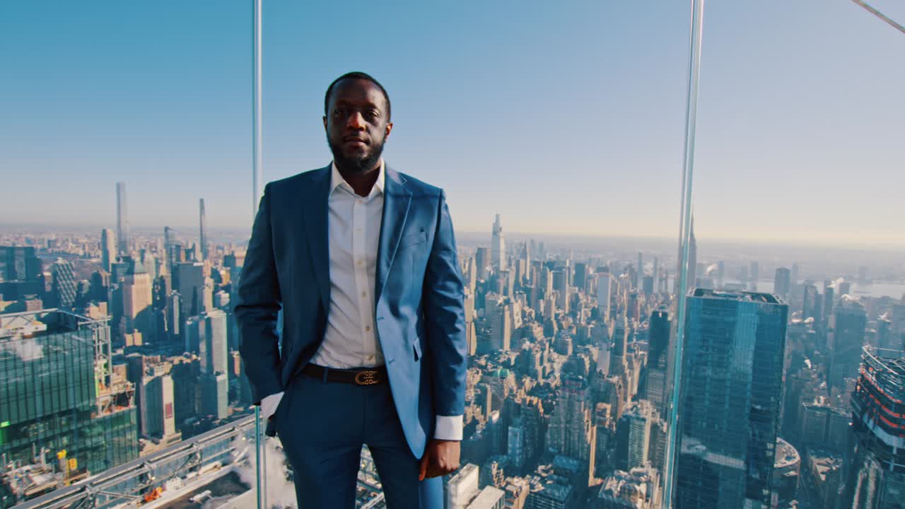 New York, USA, 15 April 2026: American businessman at observation deck overlooking New York City skyline. Medium shot of man in suit standing behind glass at high altitude skyscraper view of Manhattan