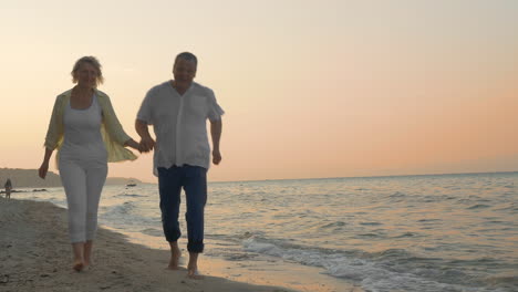 Pareja-Mayor-Corriendo-En-La-Playa-Al-Atardecer