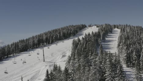 Ski-lift-and-downhill-track-one-at-Kope-ski-resort-Slovenia-in-the-daytime,-Aerial-dolly-in-shot