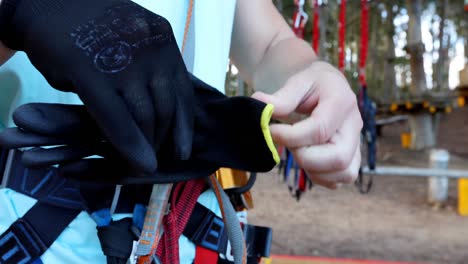 man putting hand gloves while standing against the zip line 4k 4k