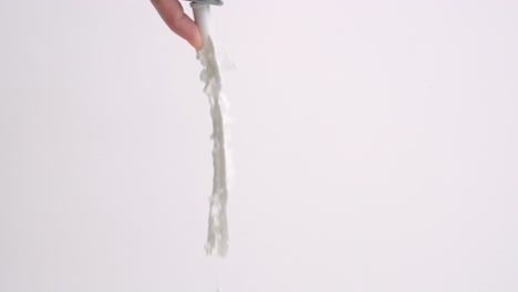 finger pressing whipped cream can tip and squirting ribbon of fresh fluffy whip creme on white backdrop in slow motion