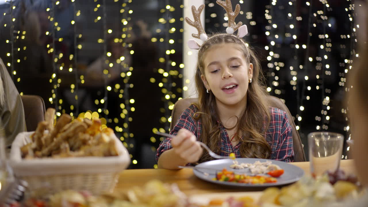 Girl wearing reindeer antlers at Christmas family dinner