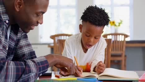 Side-view-of-black-father-helping-his-son-with-homework-at-comfortable-home-4k