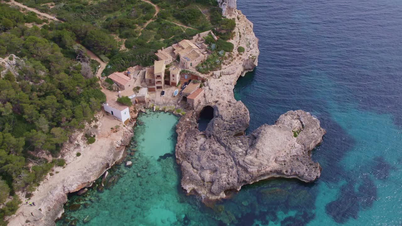 Top down of of S'Almonia beach a bay with rugged cliffs and houses, aerial