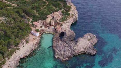 top down of of s'almonia beach a bay with rugged cliffs and houses, aerial