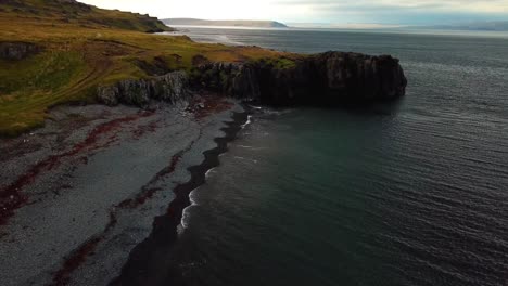 aerial landscape view of iceland north coast cliffs, with ocean waves crashing on the shoreline, at dusk