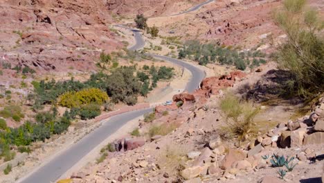 camión conduciendo en una remota carretera sinuosa del desierto a través de un paisaje seco, accidentado y rocoso en jordania, oriente medio