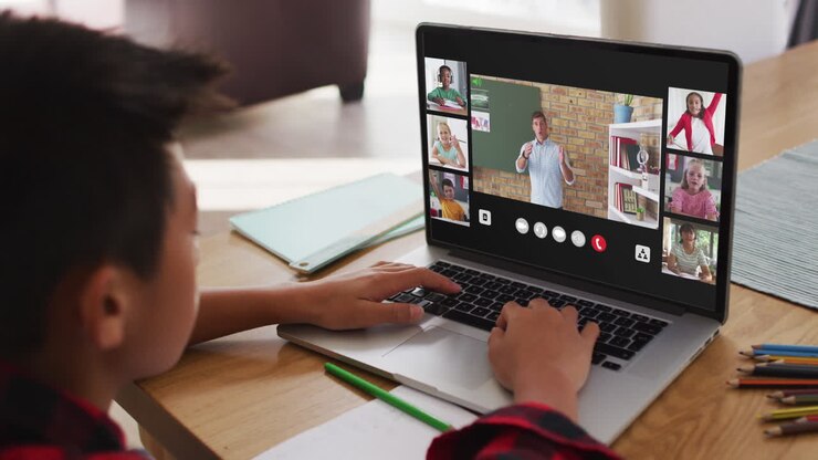 Scolaro che usa il laptop per una lezione online a casa, con un'insegnante di diverse origini e la classe sullo schermo