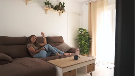 young woman watching tv in living room and using remote