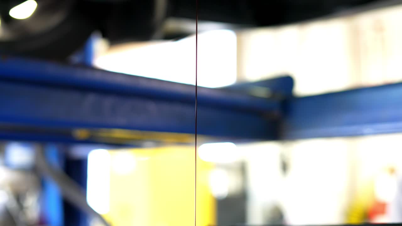 siguiendo el aceite goteando lentamente del cárter de aceite debajo del automóvil hacia la captura de aceite en el taller mecánico