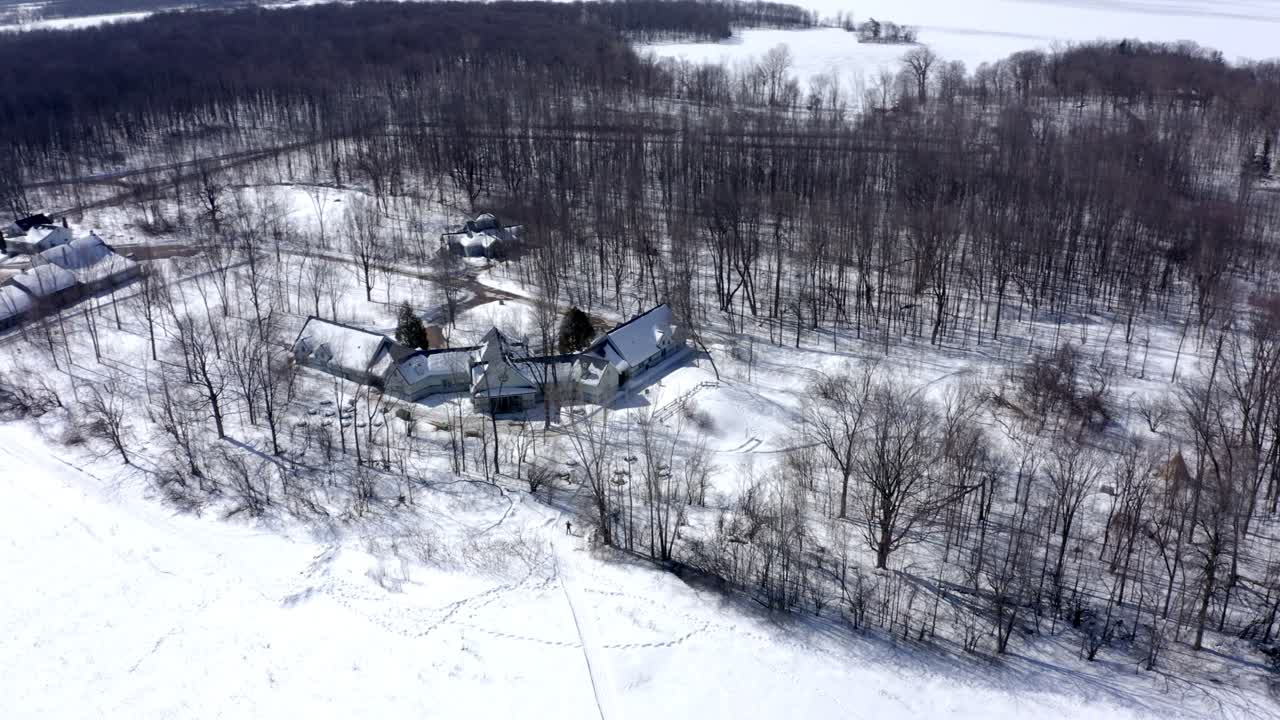 샬레 근처의 화창한 겨울날 숲 속의 노르딕 스키 선수에게 드론이 쐈습니다.