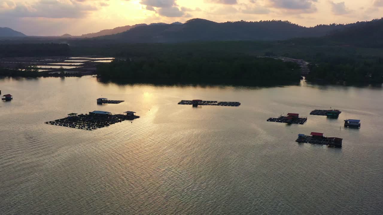 una granja de peces flotante tradicional en aguas tranquilas, instalación de acuicultura para criar peces y camarones, vista aérea del atardecer