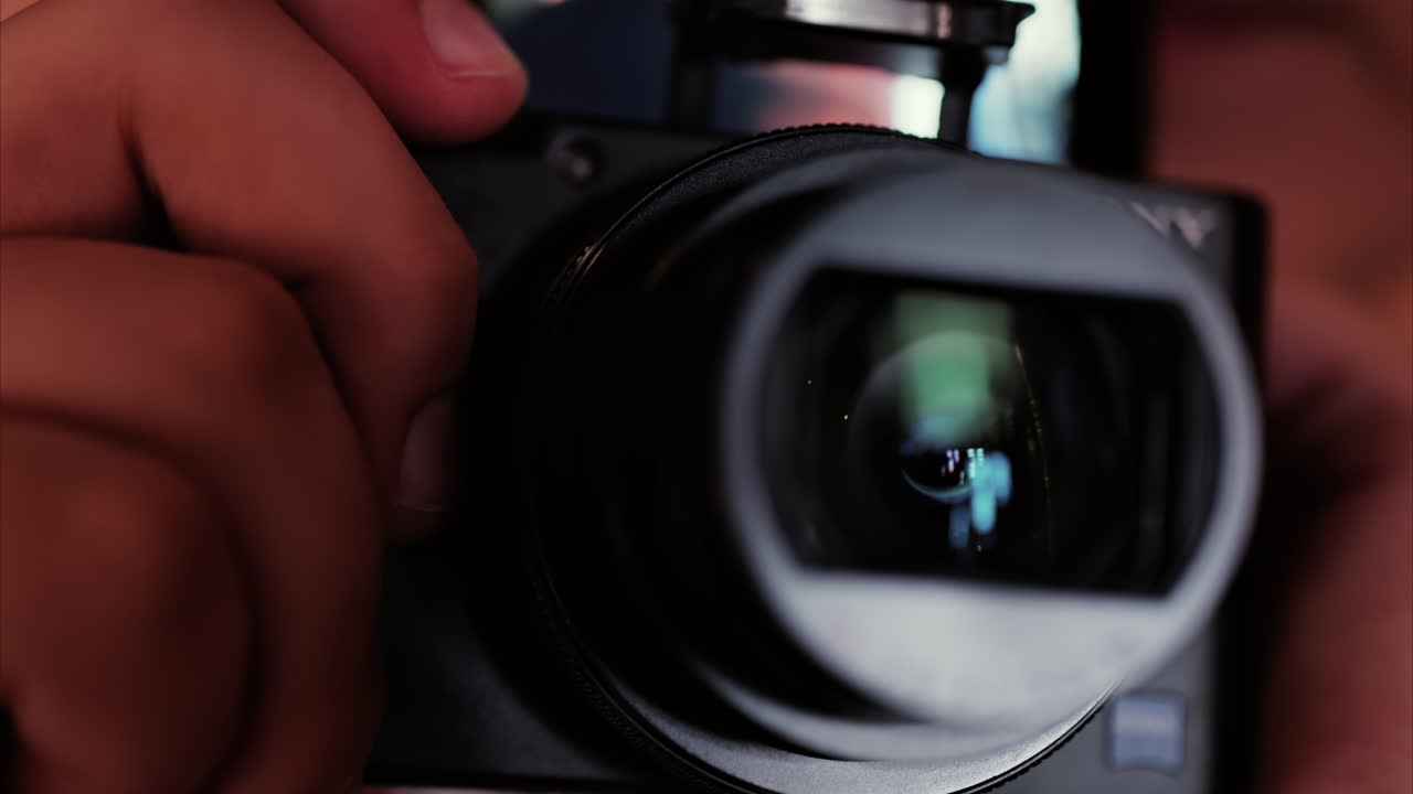 Close up of a digital camera lens held by a child, showing reflections in the glass
