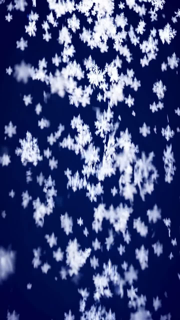 Abstract video concept with a top-down angle capturing white snowflakes against a deep blue