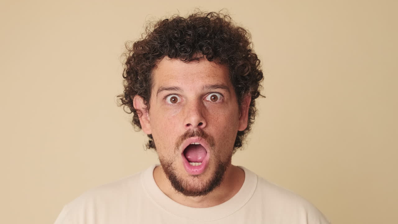 Young Man with Curly Hair Reacts with Surprise and Shock
