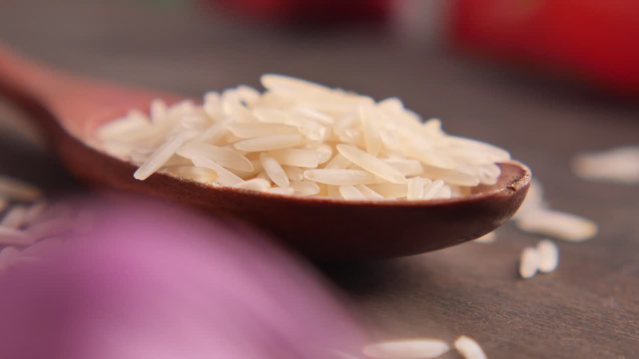 Primo piano di riso bianco crudo in un cucchiaio di legno.