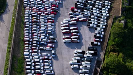drone empujado inclinado hacia abajo sobre coches apretadamente estacionados esperando transporte y venta