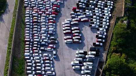 drone push in tilt down over tightly parked cars awaiting transport and sale