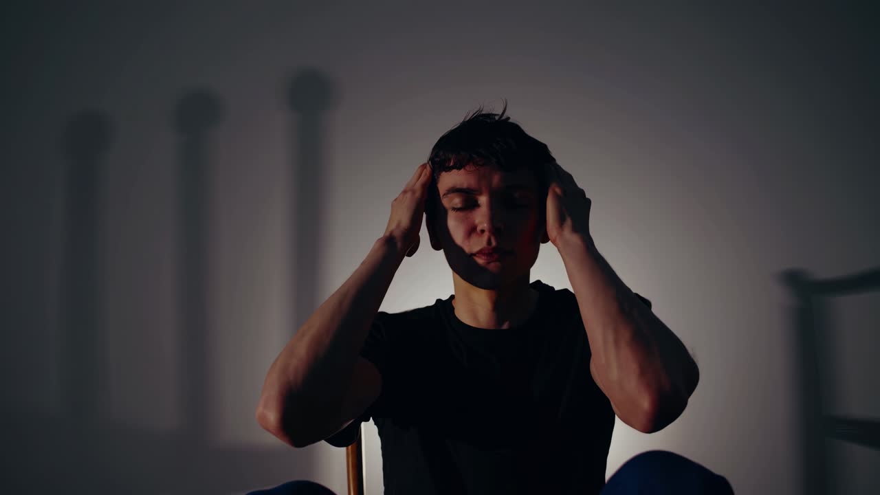 Dramatic video scene with a silhouette of a person seated, head in hands