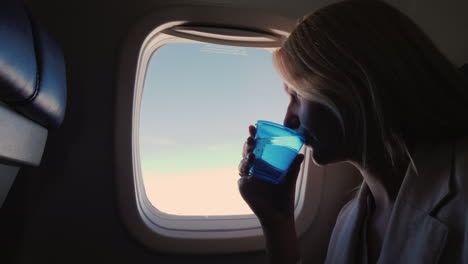 a female passenger airliner drinks water from a plastic cup