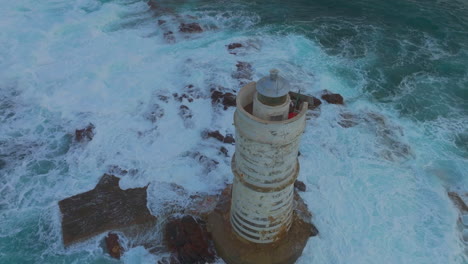 la grandeza nocturna: puesta de sol en el famoso faro de mangiabarche con las olas que se estrellan en cerdeña