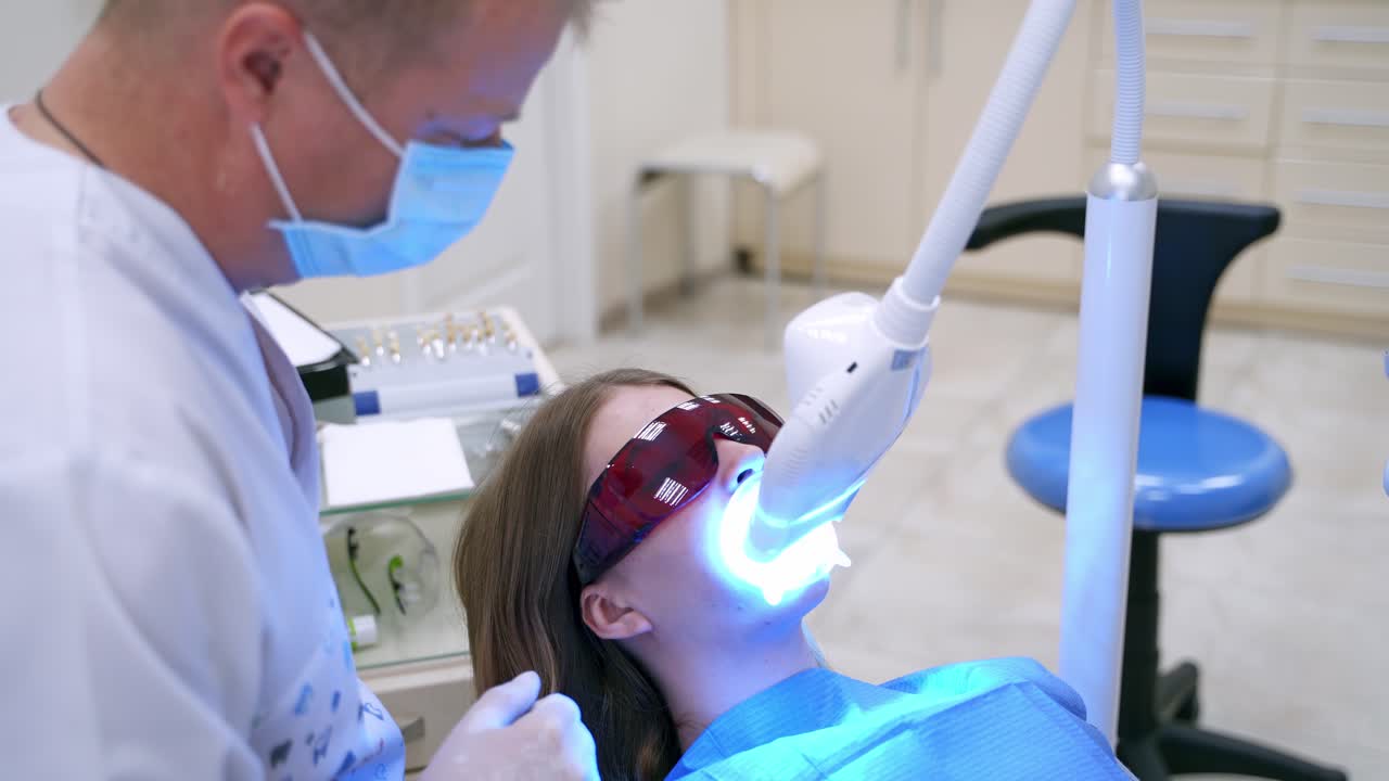 Modern equipment at dental clinic. Female patient lying in medical chair in special glasses at dentistry center. Dentist treating patient with new technology.